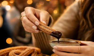 Manos mojando churro en chocolate